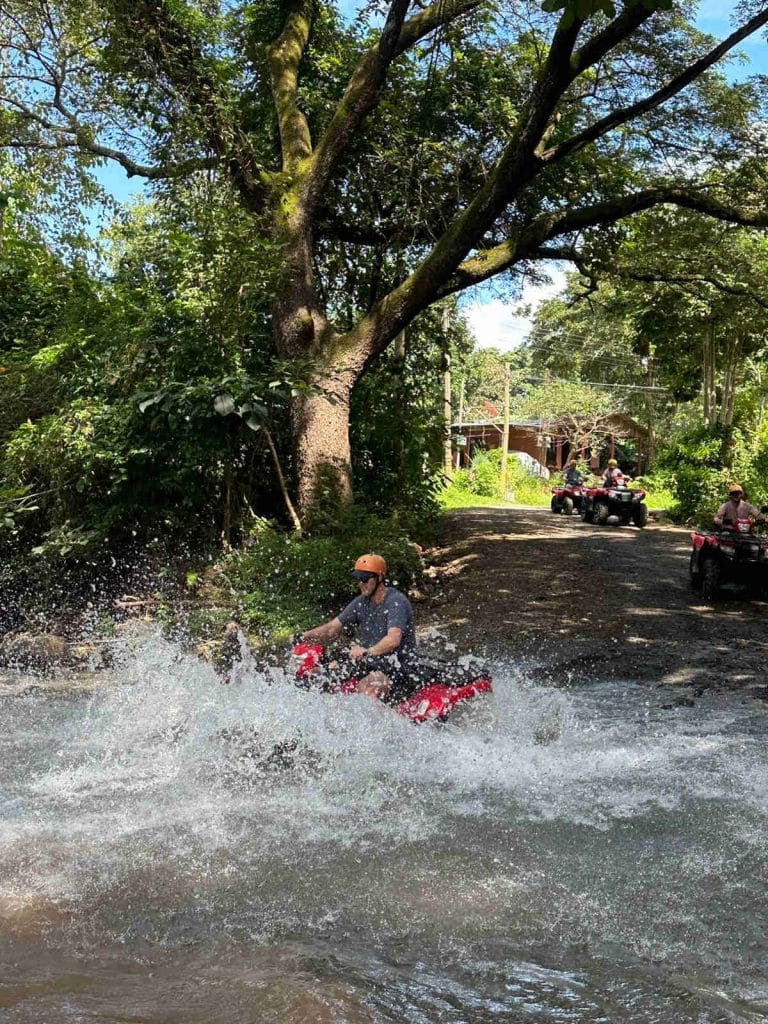 ATV driving through a river on the  jungle backtrails of Playa Potrero, Guanacaste