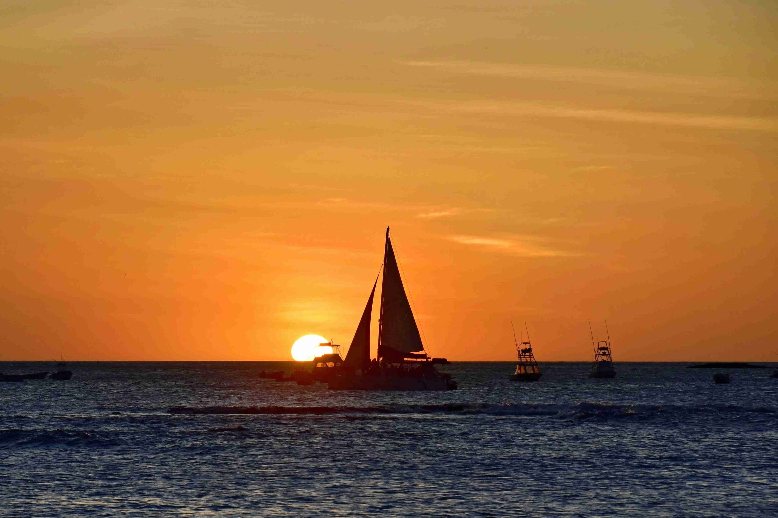 Catamaran passing the setting sun on the Pacific Ocean off of the coast of Playa Potrero, Costa Rica